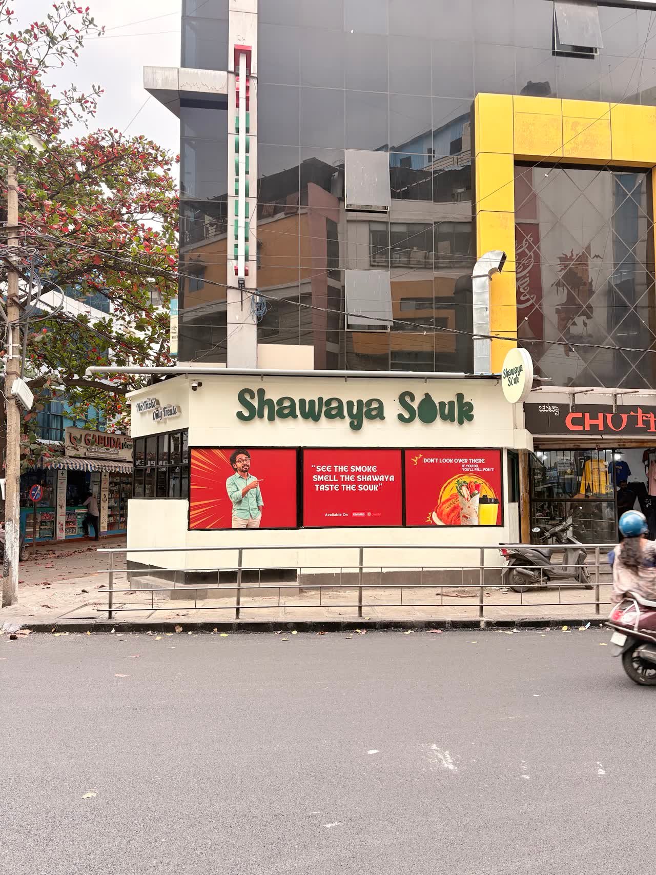 The Shawaya Souk shopfront on Tavarekere Main Road, with its green script sign and red promo banners.